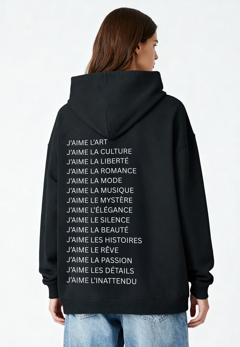 Schwarze Kapuzenjacke mit weißen Texten auf dem Rücken, die "J’aime"-Aussagen zeigen. Weicher Stoff, oversized Schnitt und Kapuze mit Kordelzug. Lässiges Design.