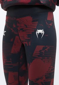 Črne in bordo pajkice z abstraktnim grafičnim vzorcem, elastičnim pasom ter srebrnim logotipom na stegni. Gladek, oprijet material.
