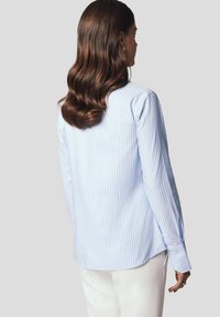 Jasnoniebieska koszula zapinana na guziki w paski, wykonana z bawełny, z długimi rękawami i prostym dołem z bocznymi rozcięciami. Gładka faktura i dopasowany krój.