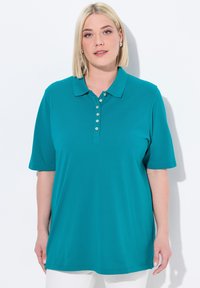 Tyrkysové polo tričko s krátkým rukávem, límečkem a řadou knoflíků na přední straně. Tkanina vypadá hladce a lehce.