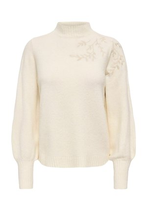 Pull en maille couleur crème à manches longues, col montant et poignets côtelés, avec une discrète broderie de feuilles sur l'épaule droite.