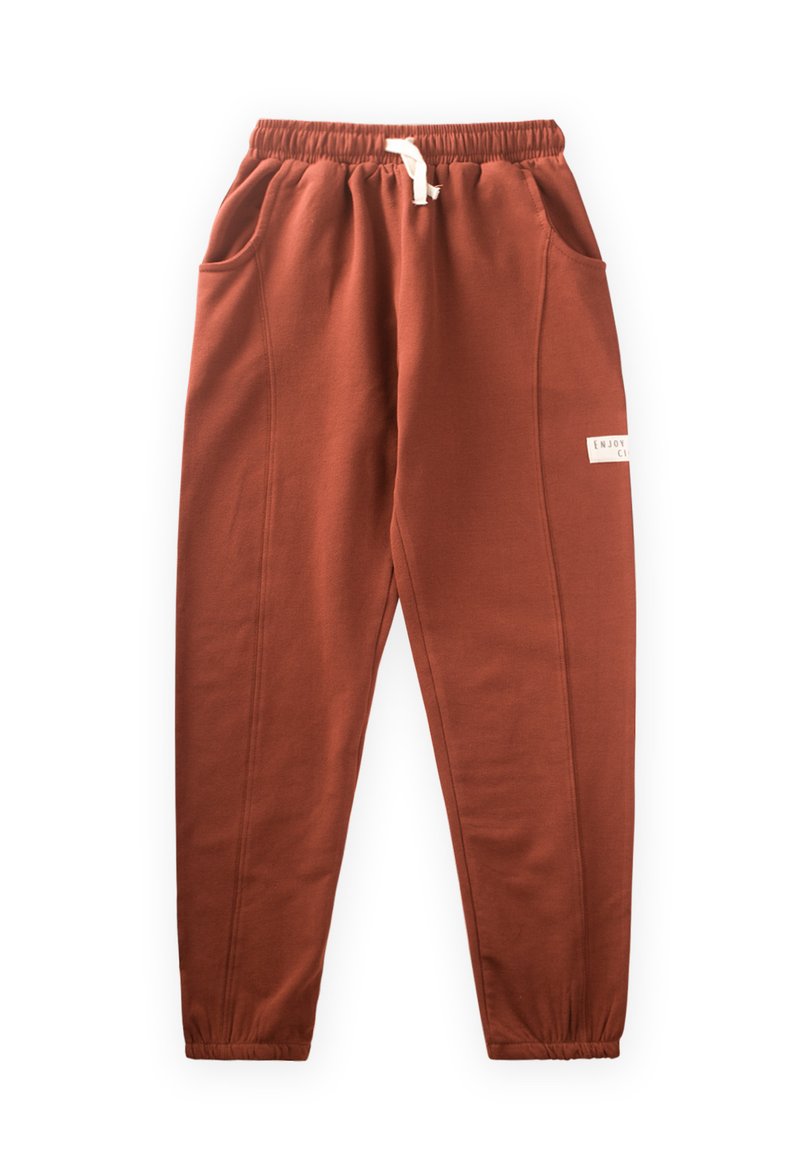 Rustfarbene Jogginghose mit elastischem Bund, Kordelzug und zwei Seitentaschen. Mit einem kleinen Logo-Patch am Bein.