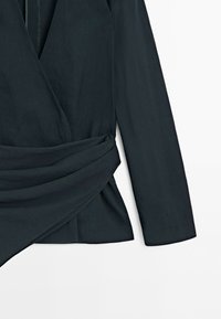 Black long-sleeve blazer with a wide fabric belt draped and wrapped around the waist on a white background.
