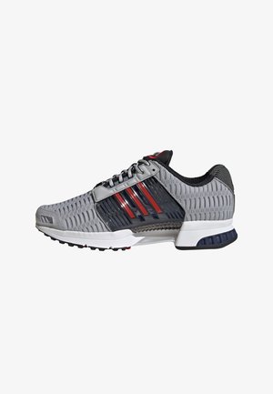Gray athletic shoe with a mesh design, red and black accents, and a cushioned sole. Features a padded collar and lacing system.