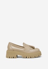 Mocassin en cuir beige avec semelle crantée épaisse et détail pompon sur le dessus, vue latérale sur fond blanc.