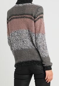 Randig stickad tröja med hög hals, i nyanser av grått, rosa och grönt. Texturerat tyg med en kraftig stickad design.