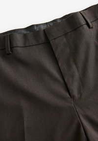 Pantalons marron ajustés avec une texture lisse, présentant une coupe droite, un devant plat et des poches latérales. Détails subtils en motif chevron.