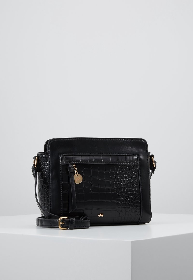 Schwarze Leder-Umhängetasche mit Krokodilleder-Textur, goldenen Beschlägen, vorderer Reißverschlusstasche und verstellbarem Riemen. Flacher Boden für Stabilität.