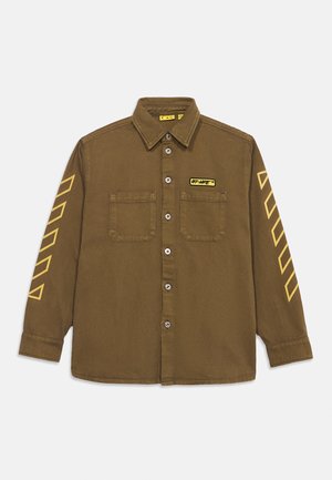 Chemise marron à boutons avec deux poches poitrine, rayures diagonales jaunes sur les deux manches, et un petit patch jaune "Off-White" sur la poitrine gauche.