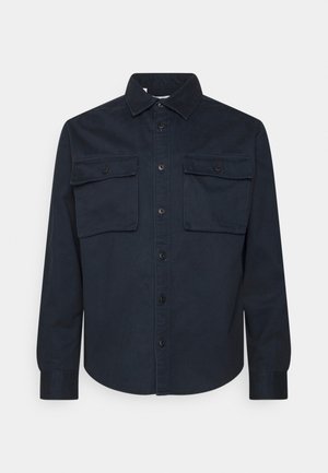 Chemise bleu marine foncé à manches longues avec col pointu et deux poches poitrine à rabats boutonnés.