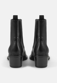 Bottines noires en cuir avec une finition lisse, panneaux latéraux élastiques et un talon bloc. Comprend une languette à l'arrière pour un enfilage facile.