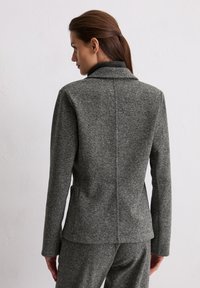 Grijze blazer met textuur, met een geknipt kraag, op maat gemaakt pasvorm en een gladde stof. De achterkant toont naaddetails en een ontspannen silhouet.