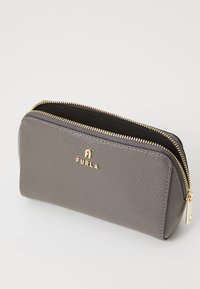 Pungă din piele gri cu fermoar, cu un finisaj texturat, accesorii metalice de culoare aurie și logo embosat. Design compact cu colțuri rotunjite.