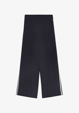 Granatowe szerokie spodnie z gumką w pasie i białymi oraz niebieskimi paskami biegnącymi wzdłuż zewnętrznych szwów.
