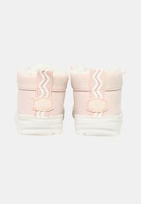 Stivali alla caviglia rosa chiaro con rivestimento in pelliccia bianca, materiale testurizzato, suola bicolore e motivo a zigzag nei dettagli posteriori. Etichetta "DUDE" visibile.