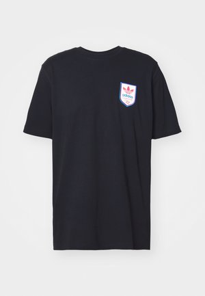 T-shirt Adidas noir à manches courtes avec un petit logo en forme de bouclier sur la poitrine gauche en rose, bleu et blanc, avec le texte "adidas Originals 72".