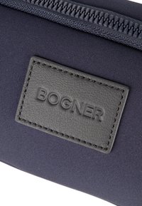 Navyblaues Stoffportemonnaie mit einem strukturierten grauen Leder-Logopatch, auf dem "BOGNER" geprägt ist, und einem passenden Reißverschluss.