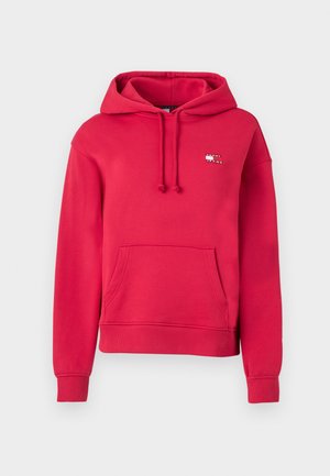 Red hoodie with a front pocket, drawstring hood, and embroidered logo on the chest. Made from soft cotton material with ribbed cuffs.
