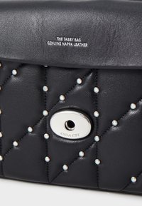 Czarna torebka z nappa skórą z pikowanym wzorem, ozdobiona okrągłymi srebrnymi i iryzującymi ćwiekami, z zamknięciem z srebrnym okuciem.
