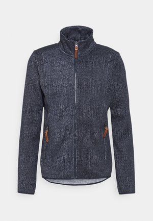 Veste zippée bleu marine texturée avec col montant et deux poches zippées dotées de tirettes marron, présentée sur un fond clair uni.