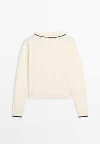 Pull crème à manches longues avec bordure noire sur le col et les poignets, vu de dos sur un fond blanc.