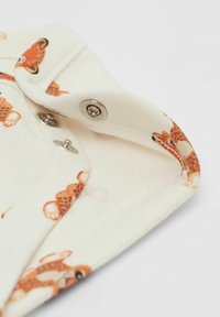 Bavlněný overal s krémovým pozadím, zdobený potiskem oranžového medvídka, s patentkami pod límcem a měkkým, texturovaným povrchem.