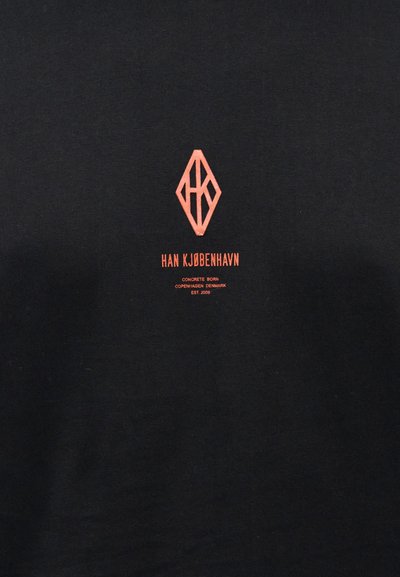 Čierne bavlnené tričko s červeným diamantom a textom "HAN KØBENHAVN" s nápisom "CONCRETE BORN" pod ním, umiestnené v strede na hrudi.