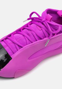Scarpa sportiva viola con tomaia in tessuto testurizzato, puntale nero lucido e dettagli in mesh per la traspirabilità. I lacci sono anch'essi viola.