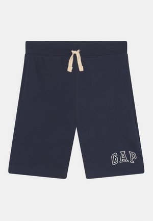 Granatowe spodenki z prążkowanym pasem i beżowym sznurkiem, z białym logo "GAP" na dolnej lewej nodze.
