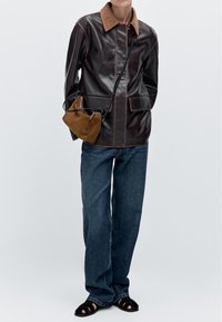 Brun läderjacka med en tan-färgad krage, fickdetaljer, kombinerad med blå vida jeans och en brun mockaväska. Svarta remsandaler fulländar looken.