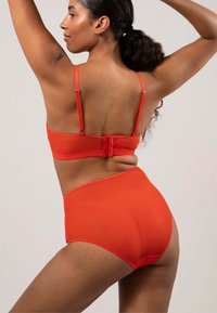 Röd bikiniuppsättning med en vadderad bralette med justerbara remmar och högmidjade trosor, båda i slät och elastisk tyg.