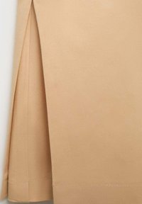 Beige sukně vyrobená z hladké tkaniny s plisovaným designem; má čistý lem a jemnou strukturu, která zdůrazňuje minimalistický styl.