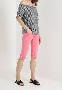Top de cuadros vichy en blanco y negro, con hombros al descubierto y mangas atadas, combinado con pantalones capri rosas y sandalias negras. Tejido suave y diseño ajustado.