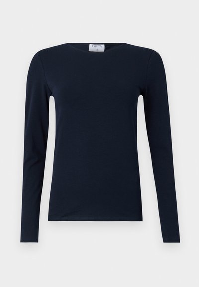 Tume sinise värvi pika varrukaga T-särk, mis on valmistatud pehmest puuvillast. Omab ümmargust kaelust, kitsast lõiget ja tavalist äärt, ilma nähtavate mustrite või aktsendita.