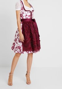 Traditionele jurk met witte bloemen stof, korte kant mouwen en een kastanjebruine versierde rok met ingewikkelde details en een sjaal.