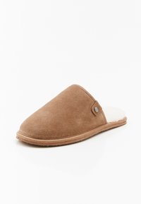 Pantofole in suede marrone, con una soffice fodera bianca e un piccolo accento metallico sul lato. Forma arrotondata, suola piatta. Texture in velluto.