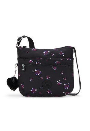 Black fabric crossbody bag with floral print in purple and pink. Features a zippered pocket, logo patch, and black pom-pom charm.