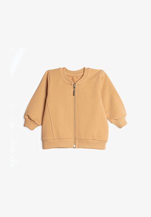 Lekko brązowa kurtka niemowlęca z długim rękawem, z prążkowanymi mankietami, kołnierzem i dolnym obszyciem, z zamkiem błyskawicznym z przodu na białym tle.