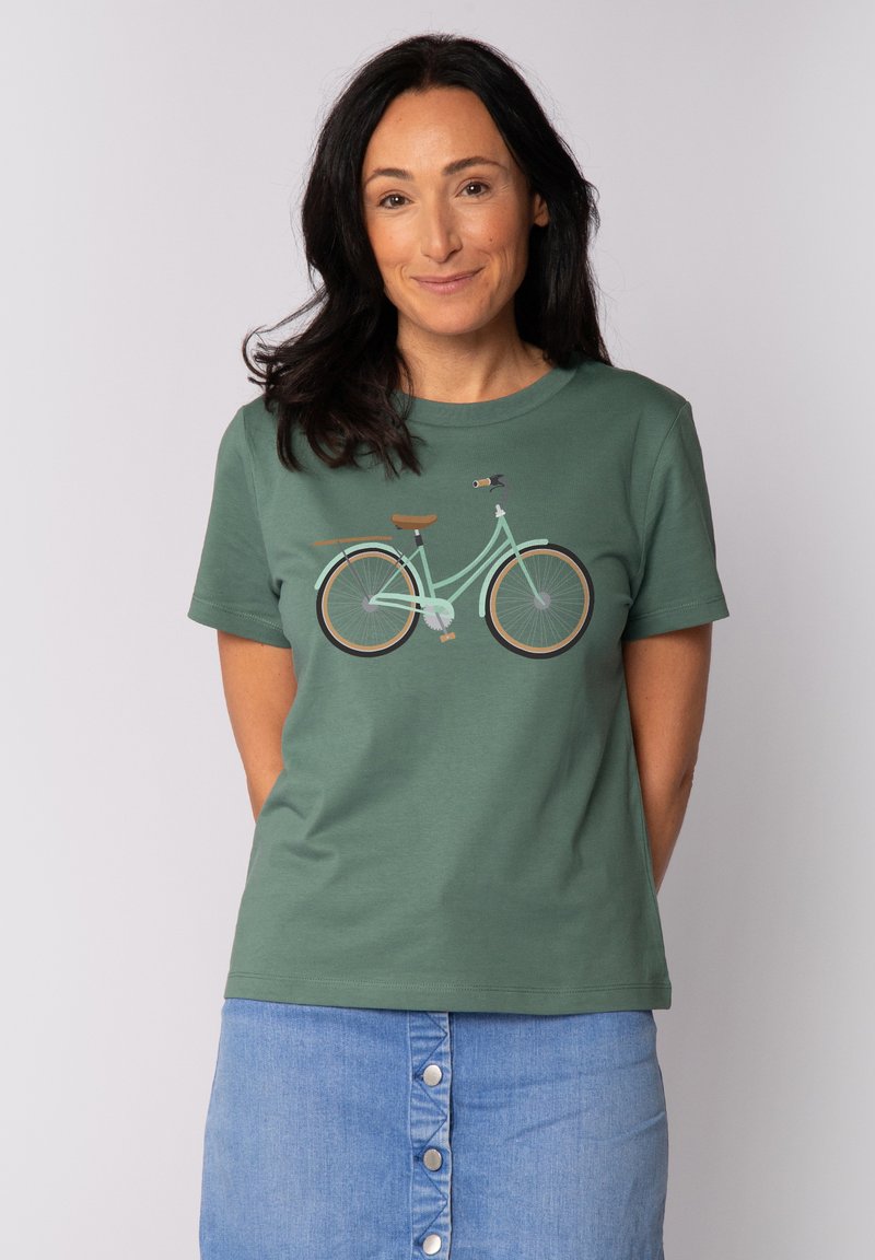 Grünes Baumwoll-T-Shirt mit einem Fahrradgrafik in Minz- und Brauntönen, runder Ausschnitt und kurzen Ärmeln, kombiniert mit einem Jeansrock.