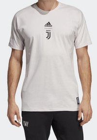 Witte crewneck t-shirt van katoenmix, voorzien van een zwart Adidas-logo en Juventus-embleem op de voorkant. Korte mouwen, casual fit.