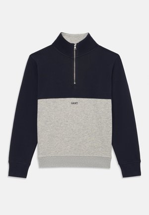 Marineblauer und grauer Halbzip-Pullover mit kontrastierendem Blockdesign, Stricktextur und kleinem Logo auf der Vorderseite.