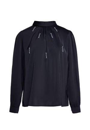 Sort bluse med lange ærmer, høj krave, løs pasform, knappede manchetter og lodrette rækker af små dekorative perler foran.