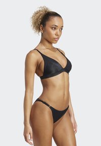 Svart bikini-set med en triangulär bralette med justerbara axelremmar och en matchande lågmidjebyxa. Strukturerad tyg med en smidig design.