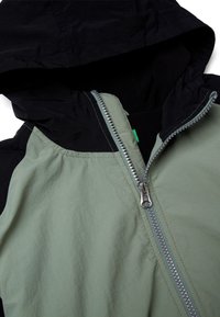 Kurtka z kapturem o dwukolorowym designie z czarną i oliwkowozieloną tkaniną, zapinana na zamek błyskawiczny, o gładkiej fakturze.