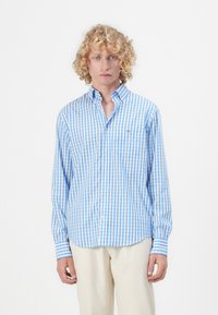 Lyseblå og hvit rutete skjorte med lange ermer og krage med knapper, med lomme og brodert logo på venstre bryst.