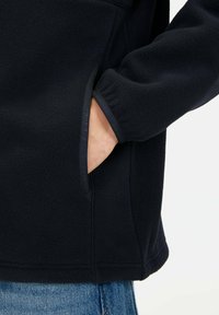 Dunkelblaue Fleecejacke mit weicher Textur. Verfügt über eine Seitentasche und elastische Bündchen. Einfaches Design, keine sichtbaren Muster oder Metallteile.
