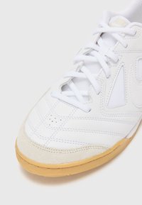 Weißer Sport sneaker mit Obermaterial aus synthetischem Leder und Mesh, ausgestattet mit einer Gummisohle, gepolstertem Zungenbereich und durchbrochenen Details.