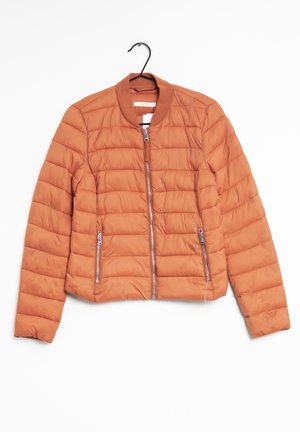 Veste bomber matelassée couleur rouille avec fermeture éclair frontale et deux poches latérales zippées, suspendue sur un cintre noir.