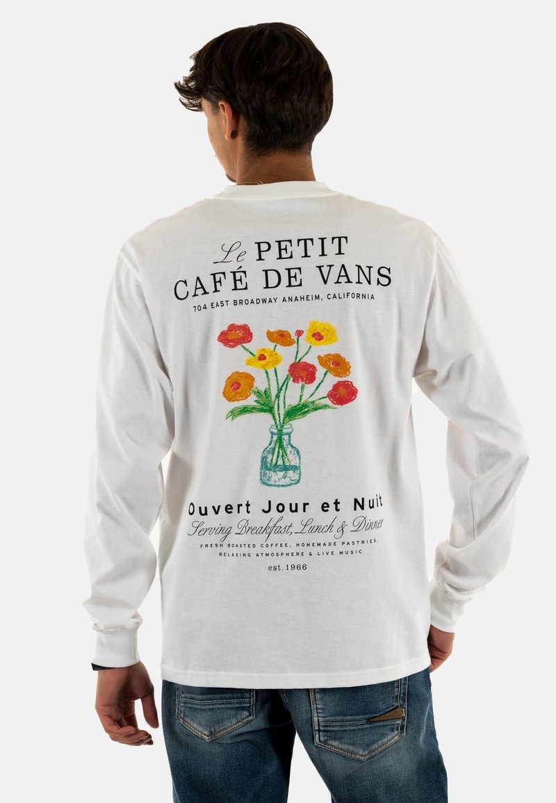 Camiseta blanca de manga larga con un gráfico de un jarrón de flores y texto negro que muestra el nombre del restaurante y detalles de ubicación en la parte posterior.