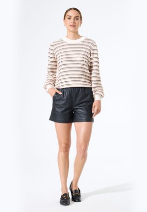 Gestreepte gebreide trui in crème, zwart en roest; gecombineerd met zwarte leren shorts; zachte textuur; relaxte pasvorm; klassieke ronde halslijn.